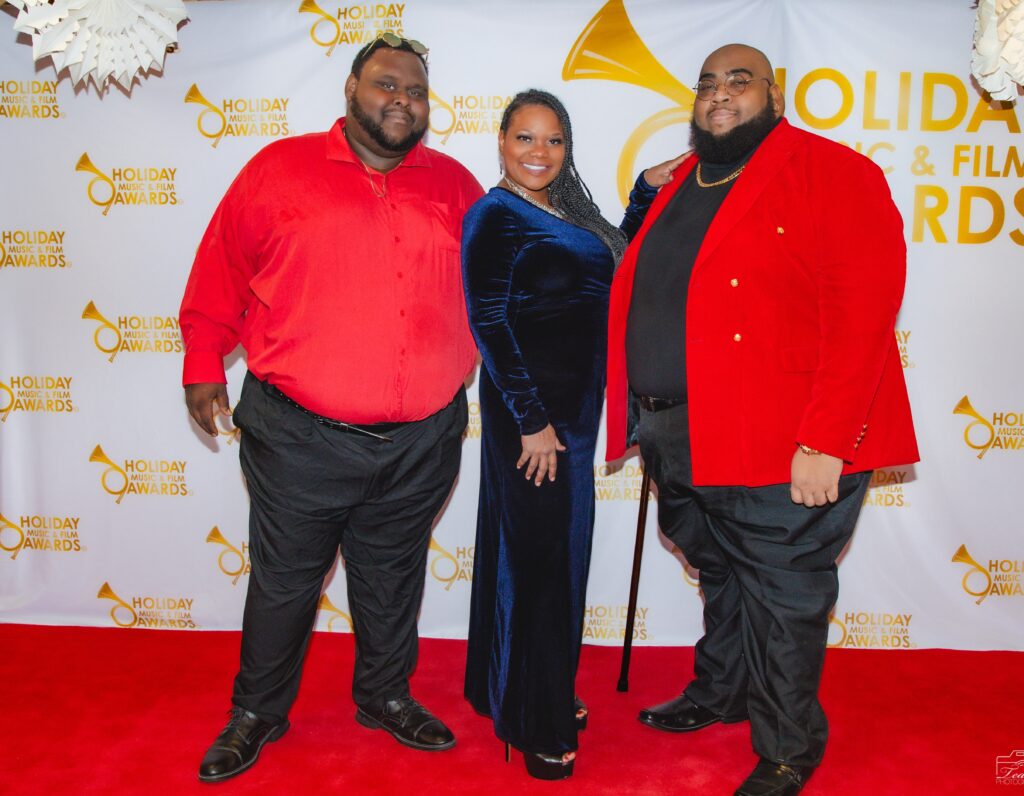 Three people posing for a picture on the red carpet.